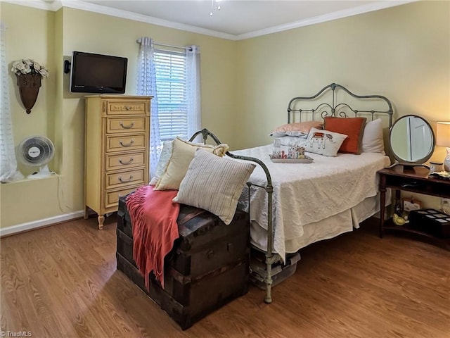 bedroom with wood finished floors, baseboards, and ornamental molding