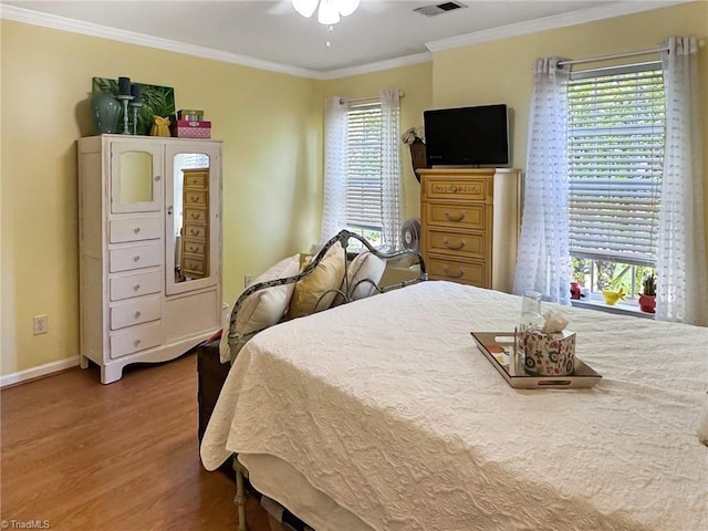 bedroom featuring visible vents, baseboards, a ceiling fan, crown molding, and wood finished floors