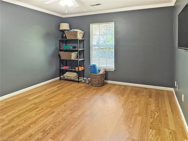 unfurnished room featuring crown molding, ceiling fan, visible vents, wood finished floors, and baseboards