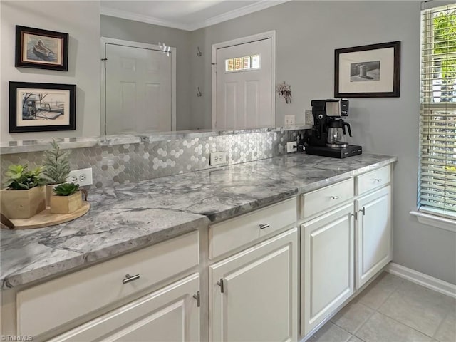 kitchen featuring baseboards, ornamental molding, light tile patterned floors, white cabinets, and decorative backsplash