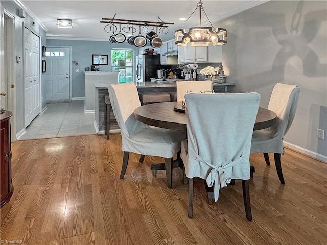 dining room featuring ornamental molding, baseboards, light wood-type flooring, and a notable chandelier