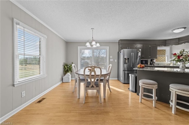 dining space featuring light wood-type flooring, an inviting chandelier, and plenty of natural light