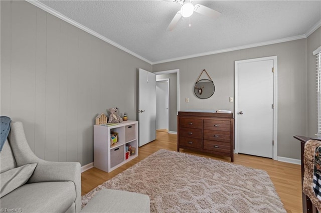 interior space featuring light wood-type flooring, ornamental molding, a textured ceiling, and ceiling fan