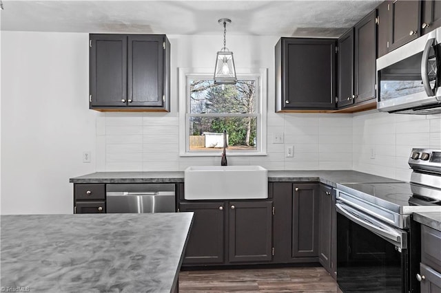 kitchen with pendant lighting, sink, appliances with stainless steel finishes, tasteful backsplash, and dark hardwood / wood-style flooring