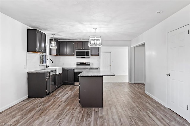 kitchen featuring pendant lighting, stainless steel appliances, a center island, and sink