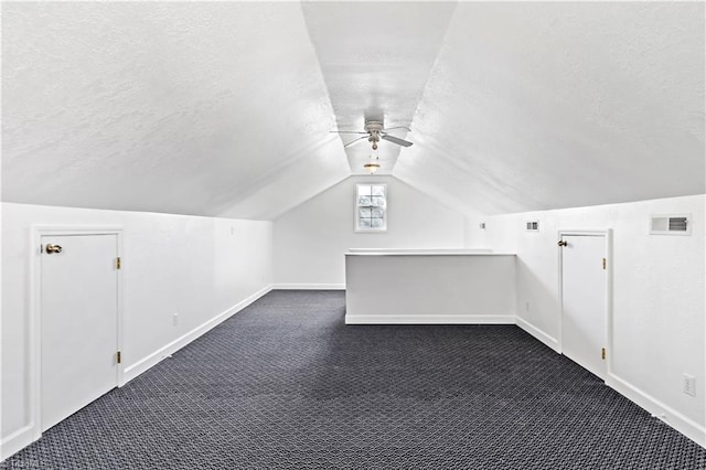 bonus room with ceiling fan, lofted ceiling, a textured ceiling, and dark carpet