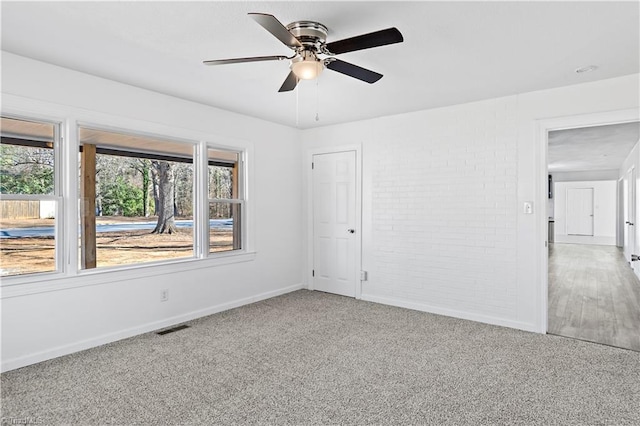 spare room with brick wall, ceiling fan, and carpet