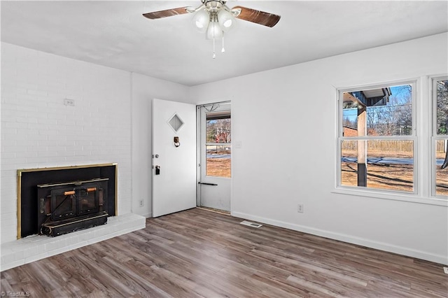 unfurnished living room featuring hardwood / wood-style flooring, ceiling fan, and a brick fireplace