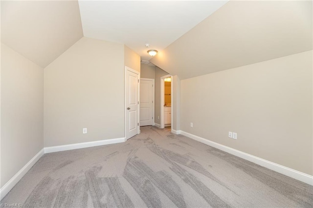 bonus room with lofted ceiling and light carpet