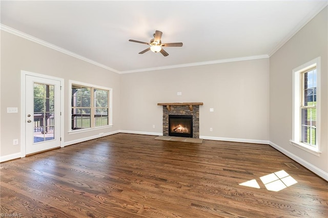 unfurnished living room featuring dark wood-type flooring, ornamental molding, a healthy amount of sunlight, and a fireplace