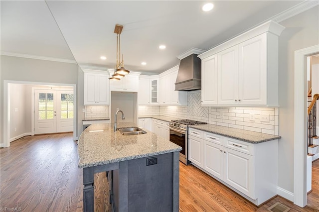 kitchen with sink, premium range hood, white cabinetry, stainless steel range with gas stovetop, and light stone counters