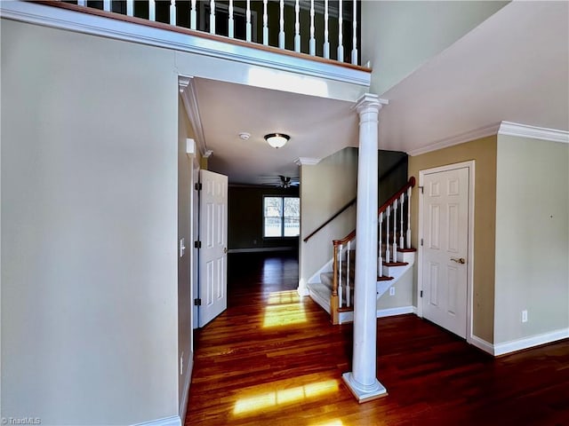 stairs featuring wood finished floors, baseboards, ornate columns, ceiling fan, and crown molding