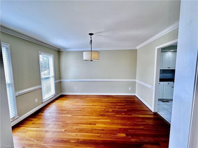 unfurnished dining area featuring baseboards, wood finished floors, and ornamental molding