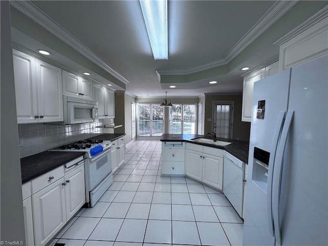 kitchen with dark countertops, white appliances, a peninsula, and a sink