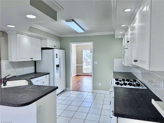 kitchen featuring a sink, white cabinets, crown molding, and light tile patterned floors