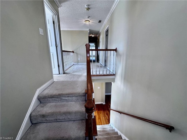 stairs featuring visible vents, a textured ceiling, wood finished floors, crown molding, and baseboards