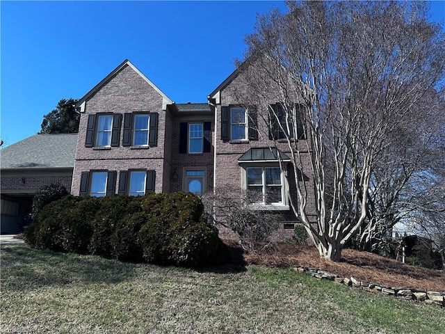 traditional-style house with a garage, brick siding, and a front lawn