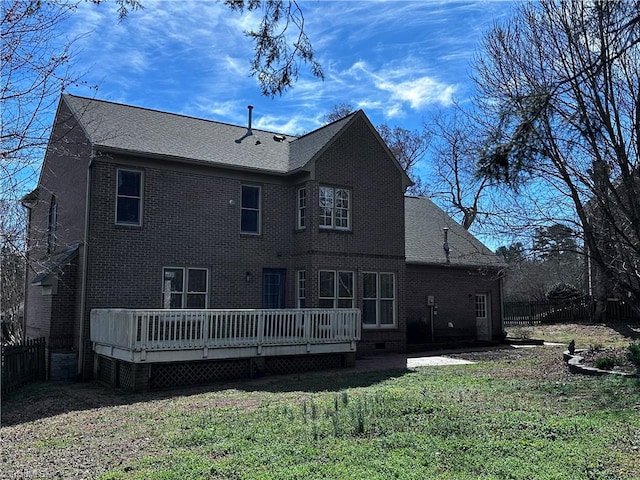 rear view of property with brick siding, a lawn, a deck, and fence