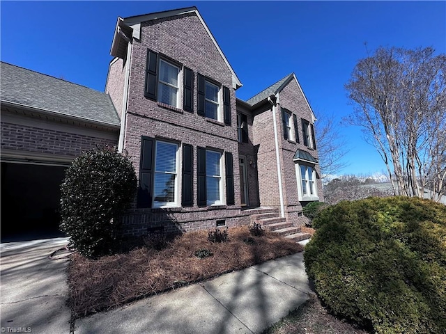 view of side of property with brick siding, crawl space, and driveway