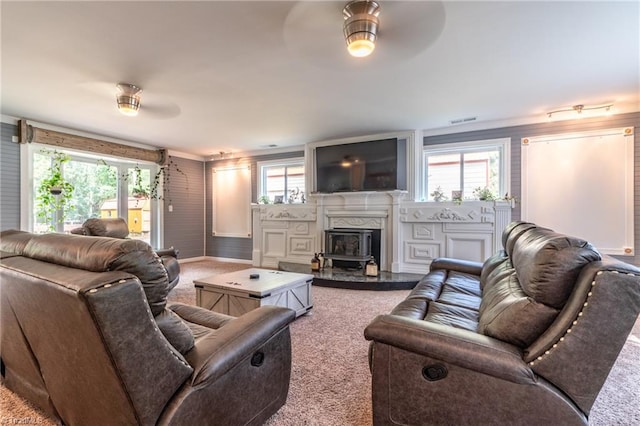 living room featuring ceiling fan, carpet, a high end fireplace, and a wealth of natural light