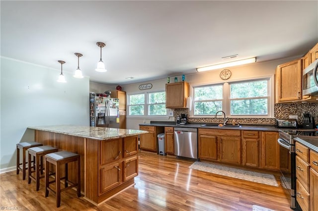 kitchen featuring light hardwood / wood-style flooring, appliances with stainless steel finishes, decorative light fixtures, and sink