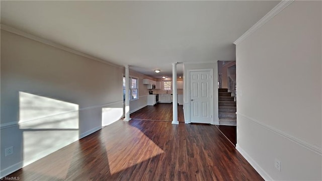 interior space featuring dark wood-type flooring, ornate columns, and ornamental molding