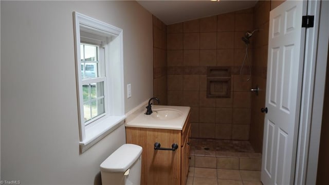 bathroom with a tile shower, lofted ceiling, vanity, and toilet