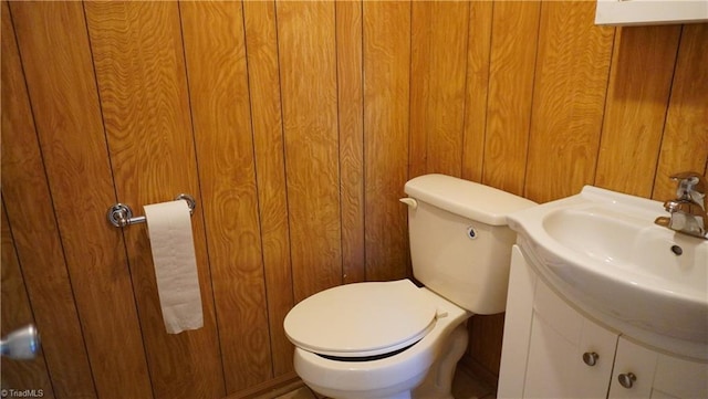 bathroom with wood walls, vanity, and toilet