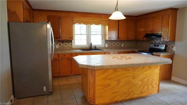 kitchen with appliances with stainless steel finishes, tasteful backsplash, tile countertops, a center island, and sink