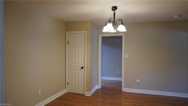 empty room featuring dark hardwood / wood-style floors and a chandelier