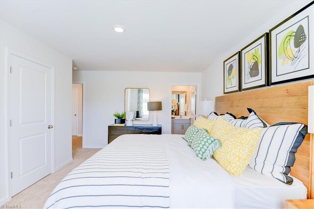 bedroom featuring ensuite bathroom and light colored carpet