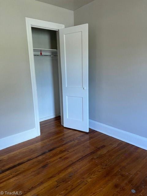 unfurnished bedroom featuring a closet and dark hardwood / wood-style floors