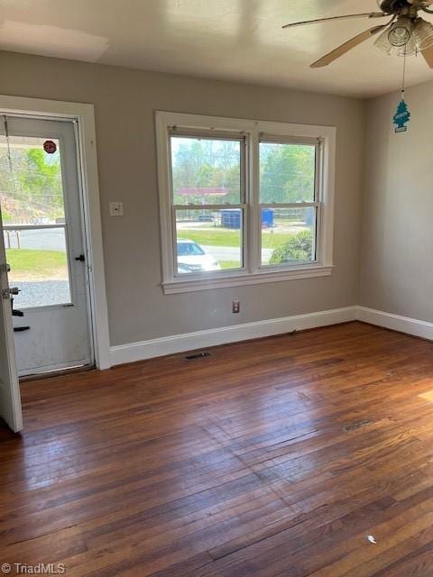 unfurnished room featuring ceiling fan, dark hardwood / wood-style floors, and a healthy amount of sunlight