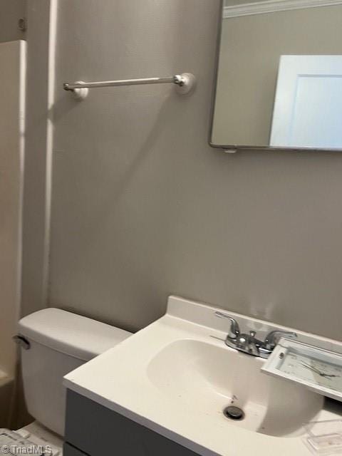 bathroom with ornamental molding, vanity, and toilet