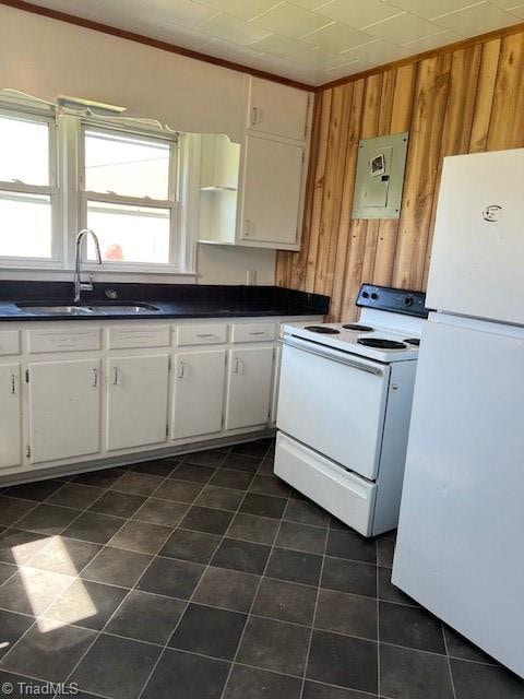 kitchen featuring white cabinets, wooden walls, sink, and white appliances