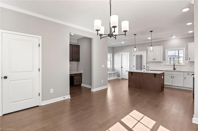 kitchen featuring pendant lighting, white cabinetry, sink, decorative backsplash, and a center island