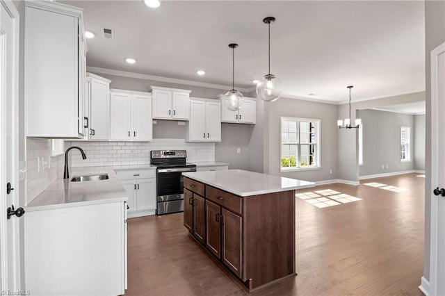 kitchen featuring electric stove, sink, hanging light fixtures, a center island, and white cabinets