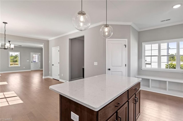 kitchen with hardwood / wood-style flooring, ornamental molding, a kitchen island, and pendant lighting