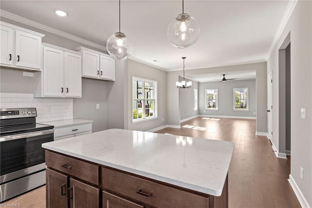 kitchen featuring electric stove, pendant lighting, ornamental molding, and white cabinets