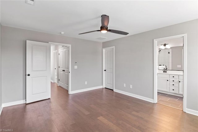 unfurnished bedroom featuring connected bathroom, dark hardwood / wood-style floors, and ceiling fan