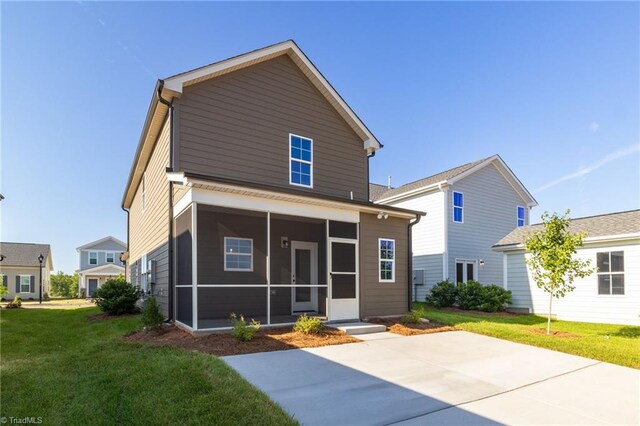 back of property with a yard, a patio area, and a sunroom