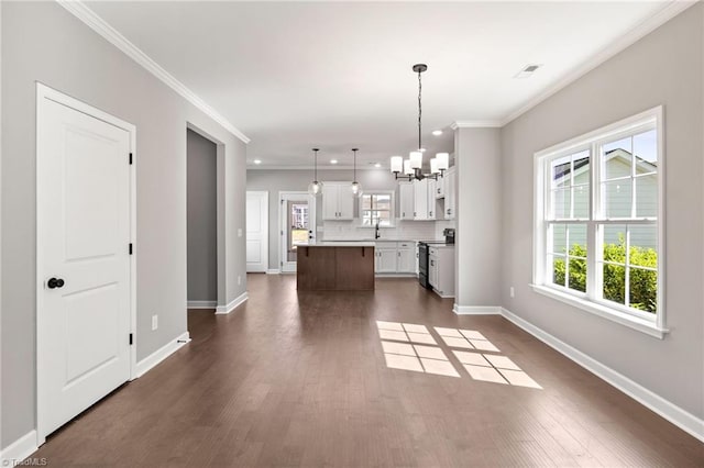 kitchen with pendant lighting, white cabinetry, ornamental molding, a center island, and electric stove