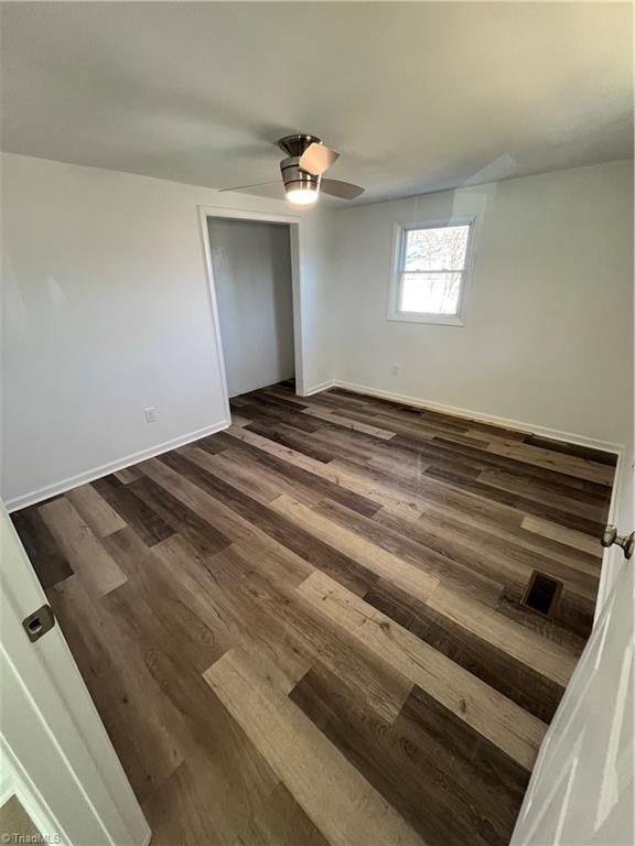 unfurnished bedroom featuring a closet, ceiling fan, and dark wood-type flooring