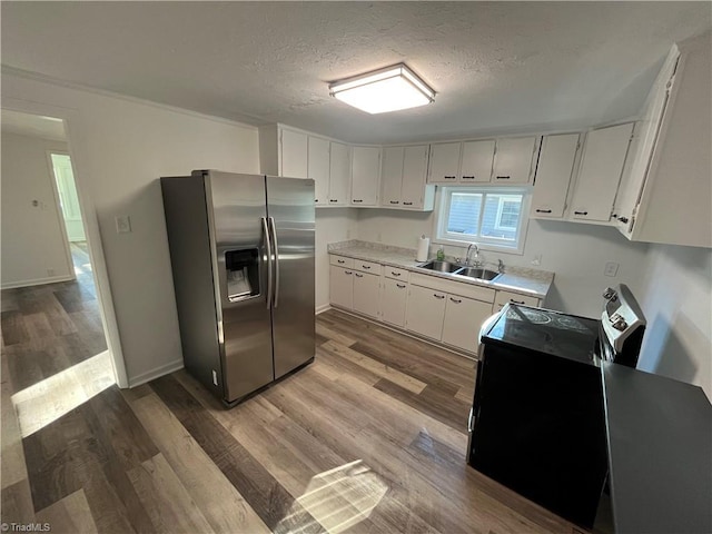 kitchen with stainless steel fridge, white cabinetry, and sink