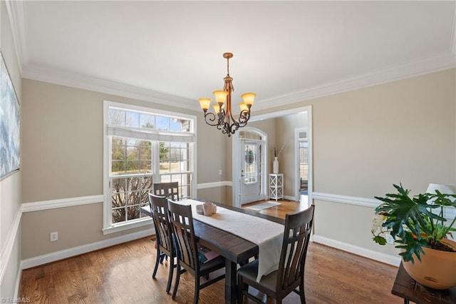 dining room featuring ornamental molding, an inviting chandelier, baseboards, and wood finished floors