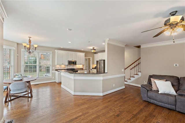 kitchen with dark wood-type flooring, ornamental molding, open floor plan, appliances with stainless steel finishes, and decorative backsplash