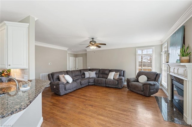 living room with light wood-type flooring, a fireplace, and crown molding