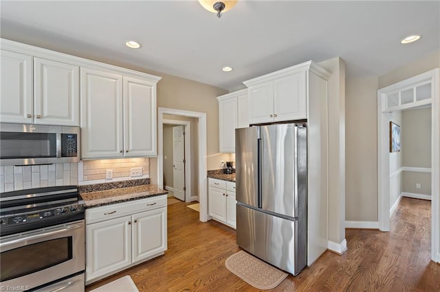 kitchen featuring decorative backsplash, white cabinets, wood finished floors, and stainless steel appliances