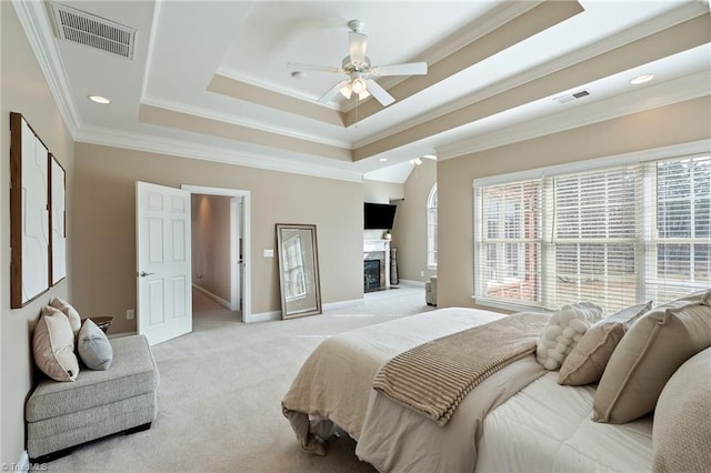 bedroom with visible vents, a raised ceiling, light carpet, and ornamental molding