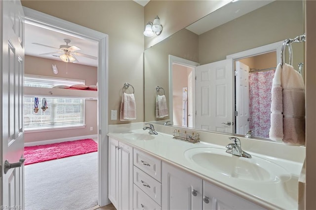 full bath featuring a sink, baseboards, a ceiling fan, and double vanity